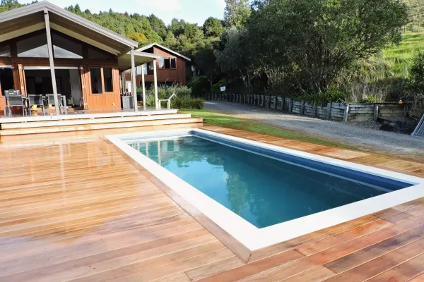 Deck around pool with house in the background