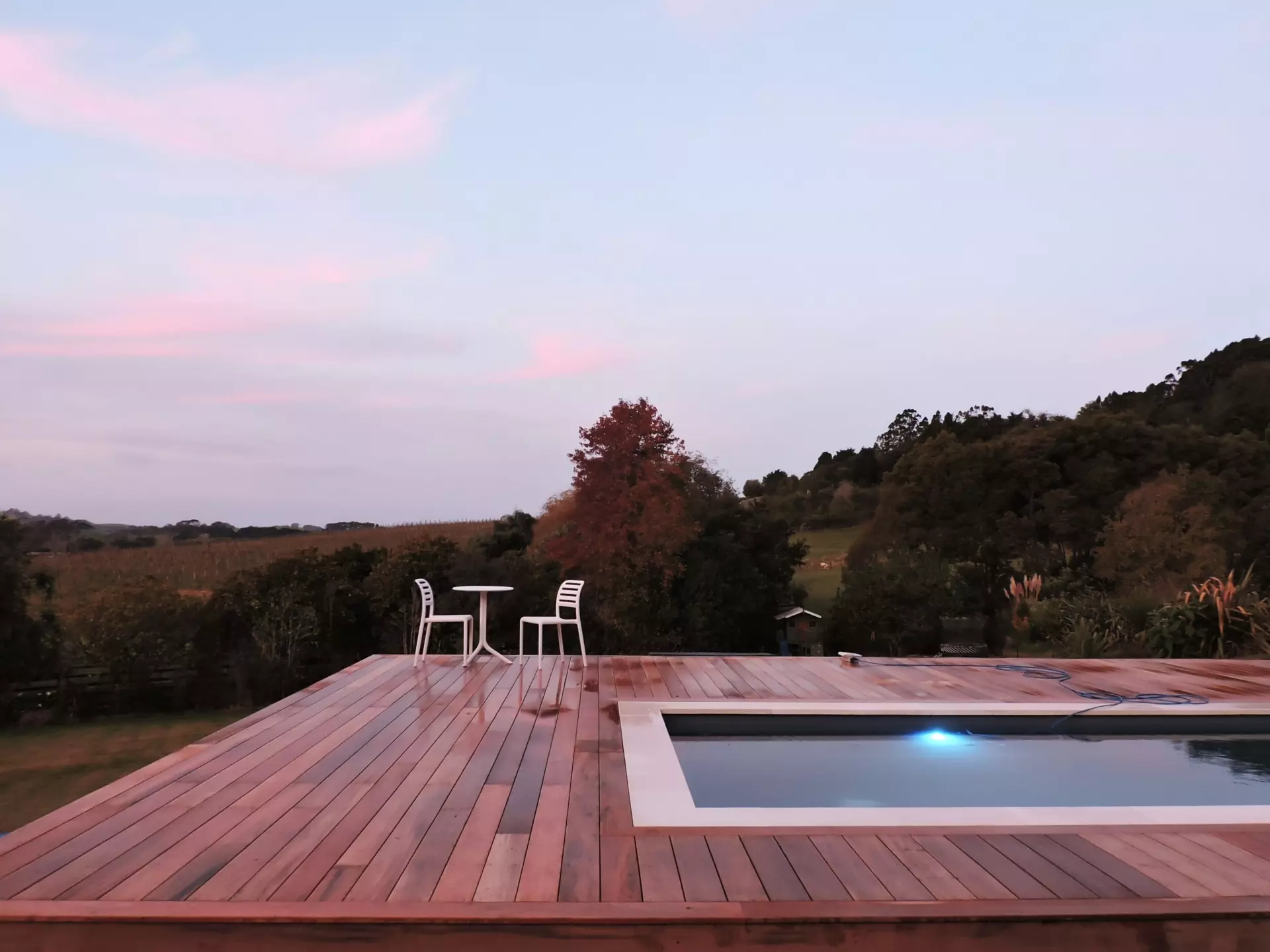 A deck built around a pool. Image taken at sunset
